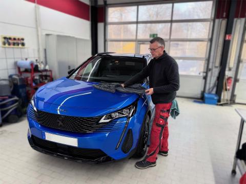 Lackversiegelung bei Autochampion24 in München – professionelle Autopflege Mitarbeiter von Autochampion24 bei der Lackversiegelung eines blauen Peugeot in der Autopflegewerkstatt in München