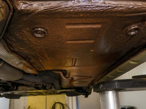 Leichter Rost unter dem Fahrzeug – trotz vorhandener Beschichtung ein Sicherheitsrisiko Leicht verrosteter Fahrzeugunterboden trotz Schutzbeschichtung – Nahaufnahme aus Werkstattumgebung, rostige Stellen gut sichtbar.