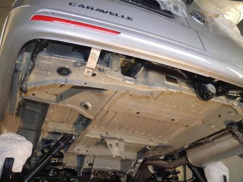 VW Caravelle: Unterboden vor Nachbehandlung – kritische Stellen ohne ausreichenden Schutz Unterboden eines VW Caravelle mit werkseitiger Beschichtung, fotografiert in der Werkstatt – gut sichtbar: ungeschützte Kanten und Anschlussstellen.