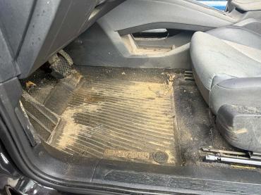 Verschmutzter Fahrerfußraum vor der professionellen Autoaufbereitung