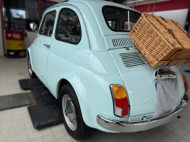 Klassischer Fiat 500 in hellblau auf der Hebebühne in der Werkstatt