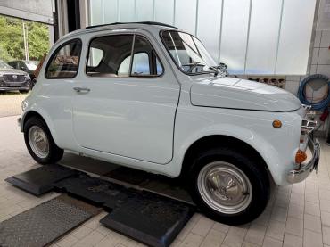 Klassischer Fiat 500 in hellblau auf der Hebebühne in der Werkstatt